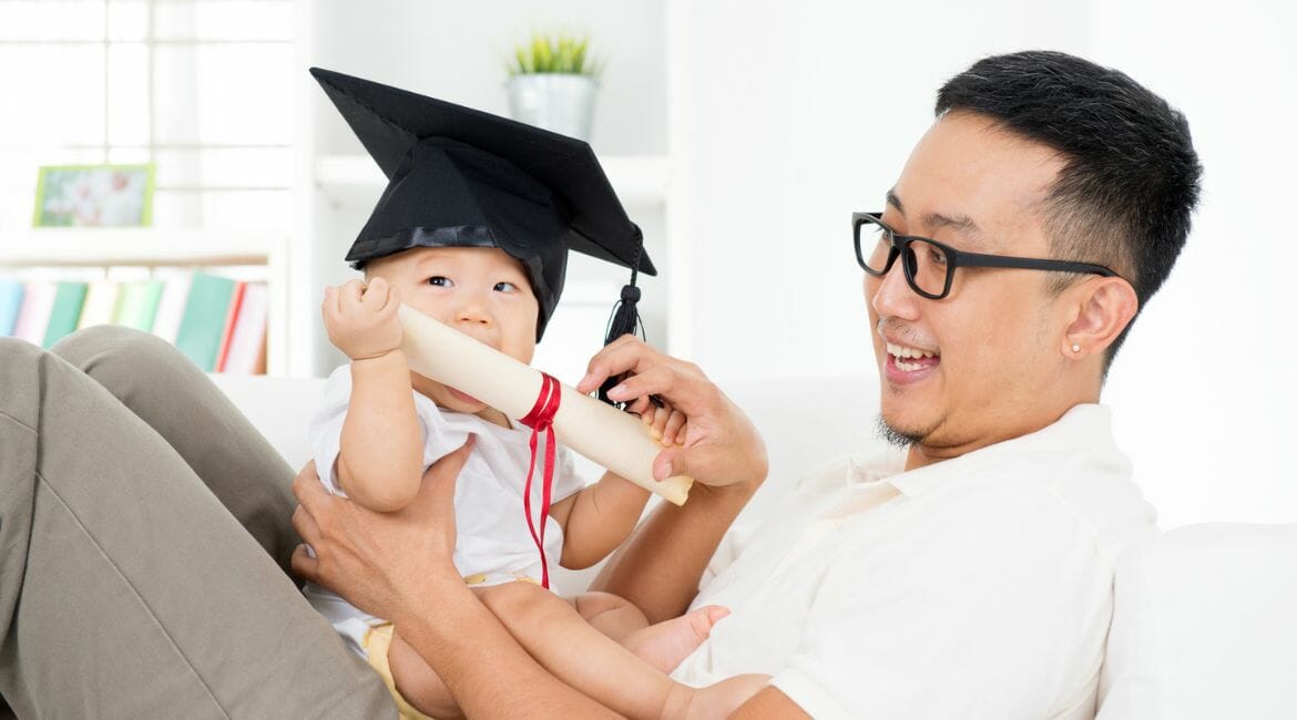 A Baby Wearing A Graduation Cap With A Man Sitting On The Couch, Emphasizing flexibility in grades during homeschool