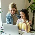 A Mother And Daughter Working On A Laptop At Home.