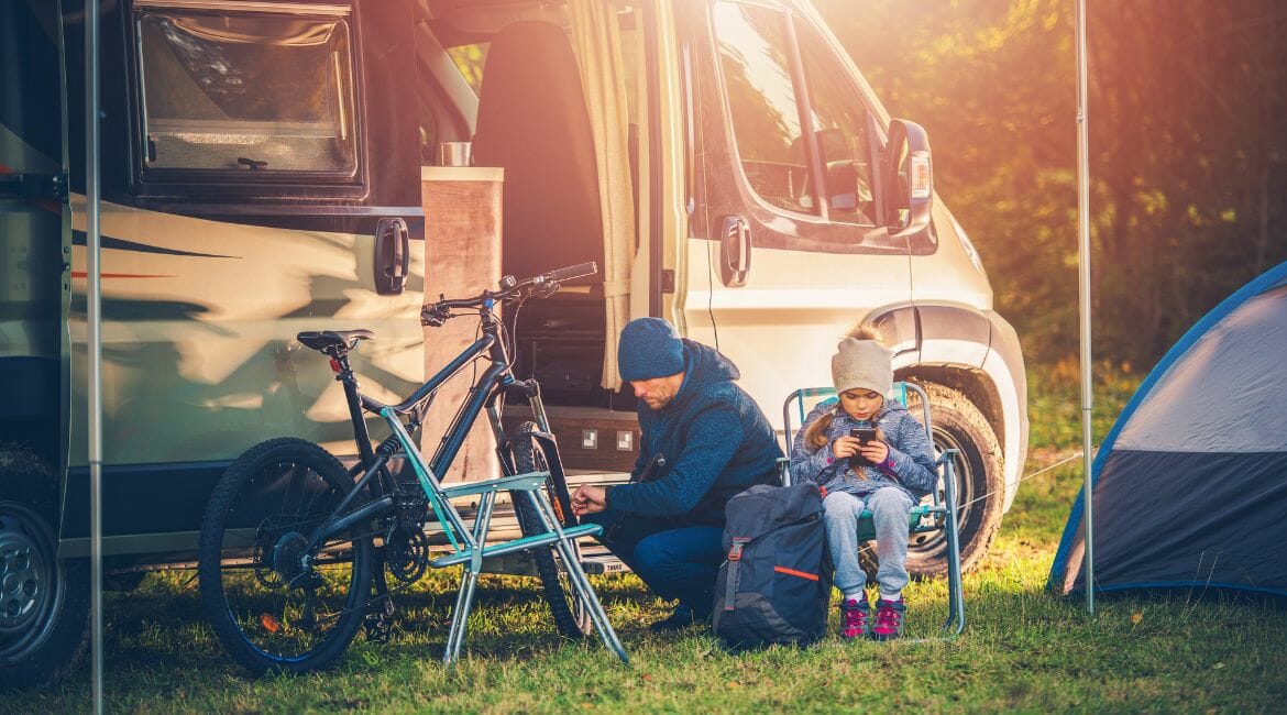 A Man And A Woman Setting Up A Tent In Front Of An Rv.