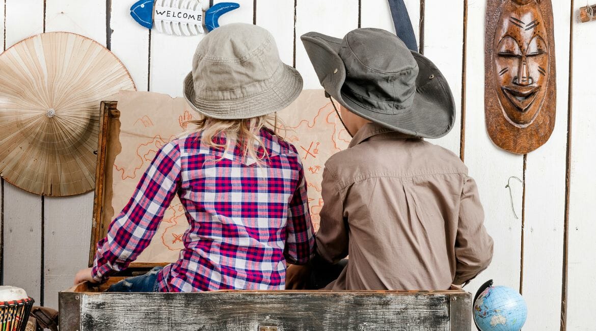 Two Children In Hats Sitting In A Wooden Crate.