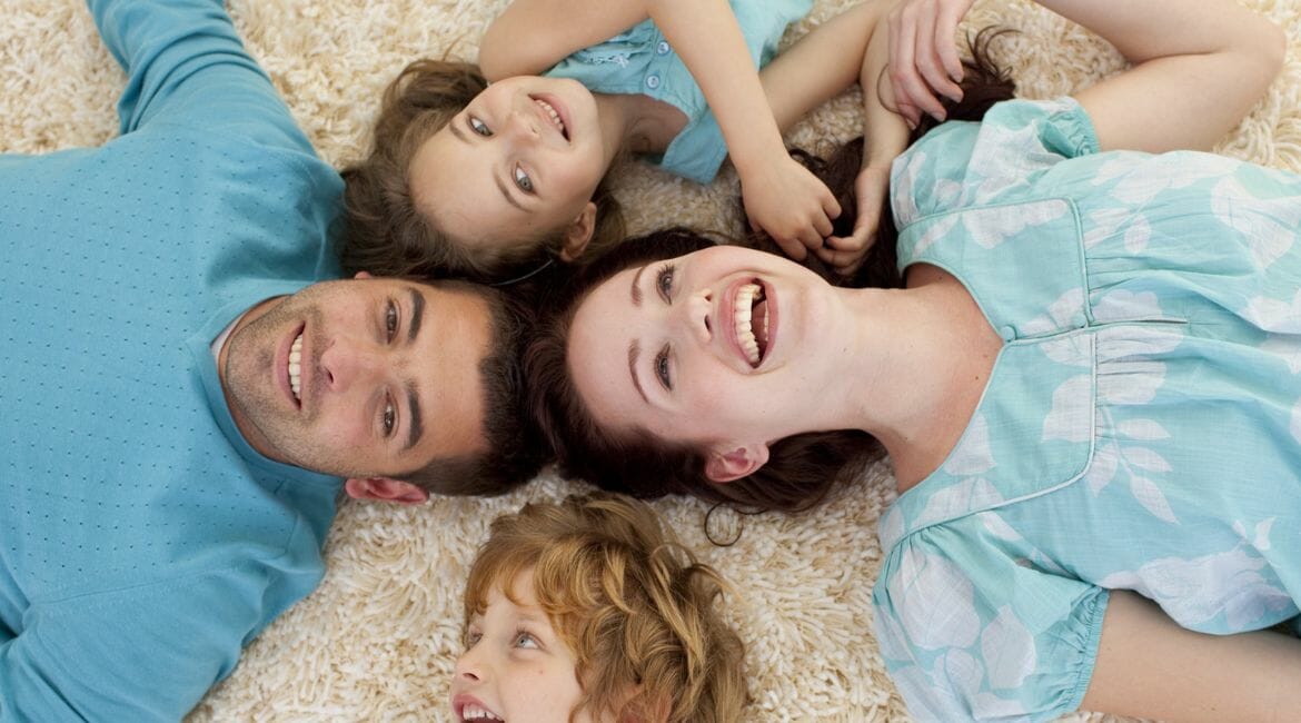 A Family Laying On A White Carpet.