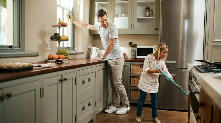 A Man And A Little Girl Cleaning A Kitchen.