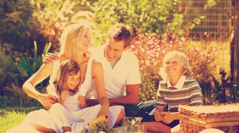 A Family Enjoying A Picnic In The Garden.